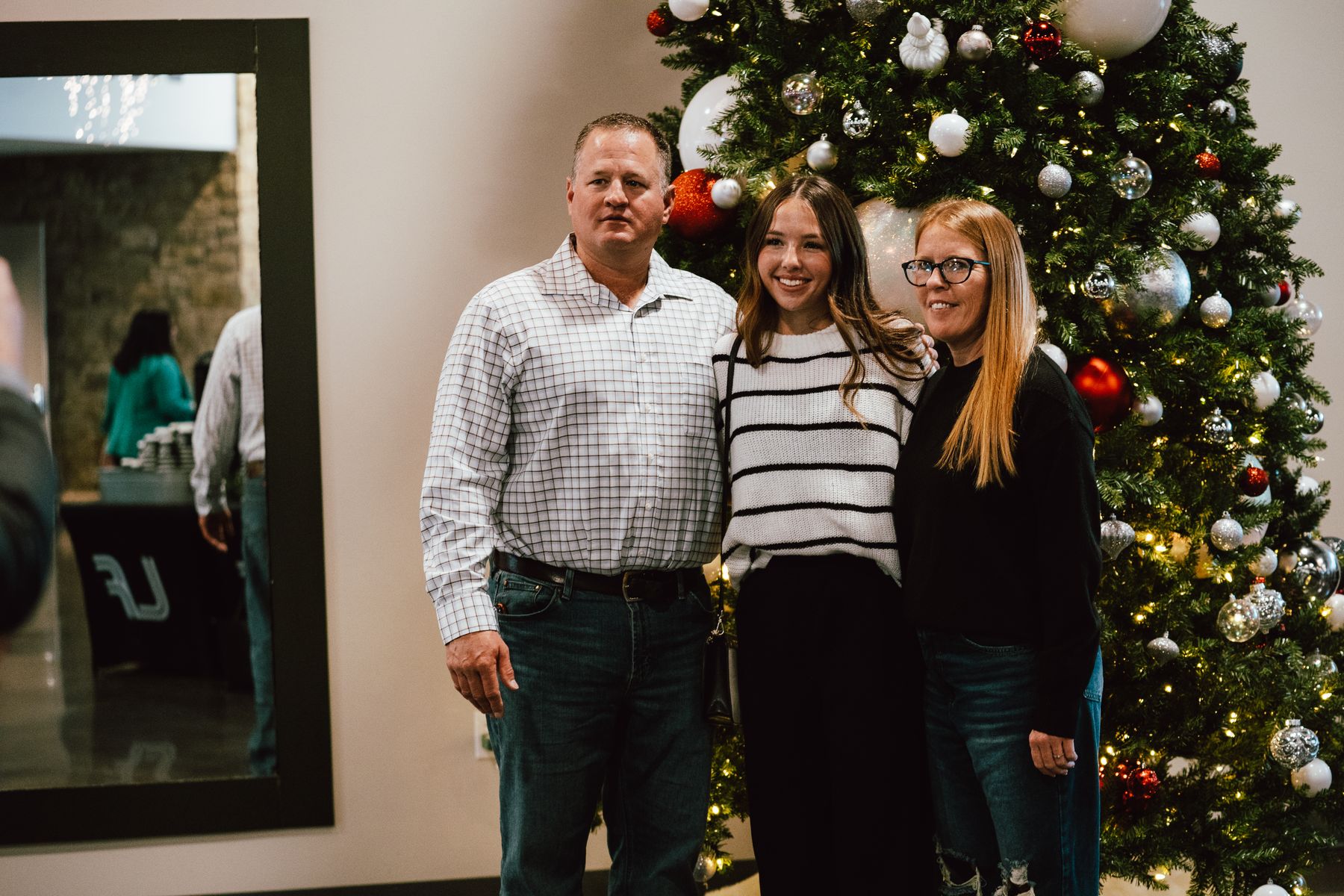 A family smiling beside the Christmas tree in the lobby